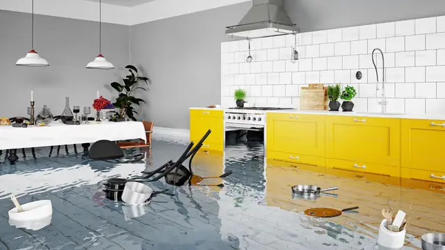 Flooded kitchen with an overturned chair and items floating in the water